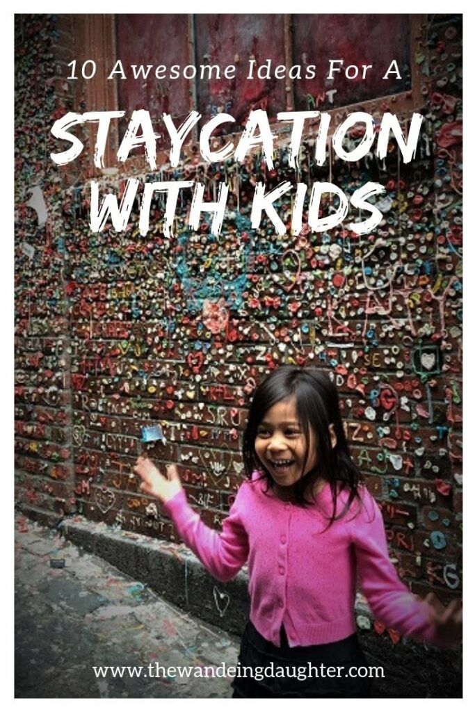 Staycation With Kids! Ten Awesome Ideas For Families | The Wandering Daughter | Creative ideas for families to spend a staycation with kids in their home town. Pinterest pin. Photo of a girl in front of a wall with wads of gum stuck to it.