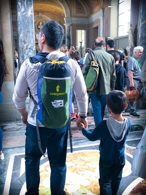 Man walking in the Vatican holding a kid's hand to prevent him from getting lost