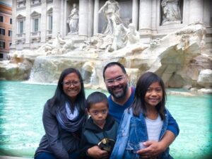 family in front of trevi fountain in rome italy