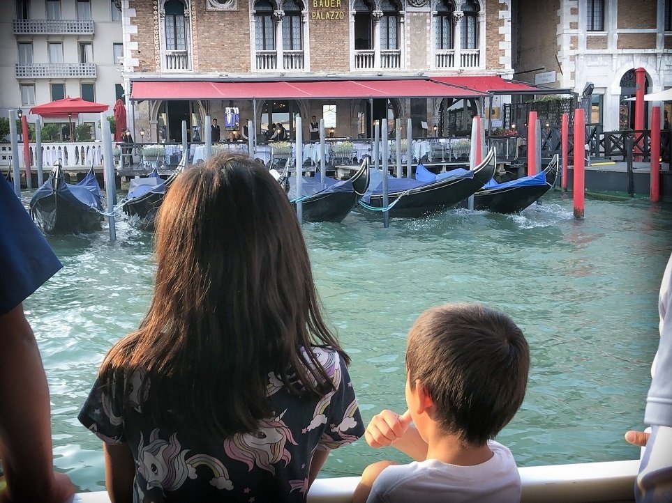 kids looking at gondolas on canal in venice italy during an Italy itinerary while doing Italy activities for kids