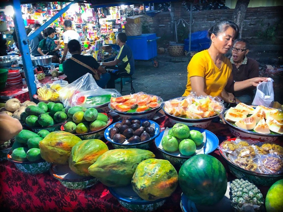 A fruit stand at a Bali night market in Gianyar, Bali in Indonesia. On display are papayas, watermelon, mangoes, oranges, and snake fruit.