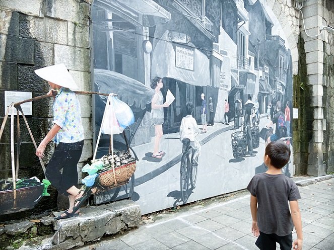 A boy walking past a mural in Hanoi, Vietnam