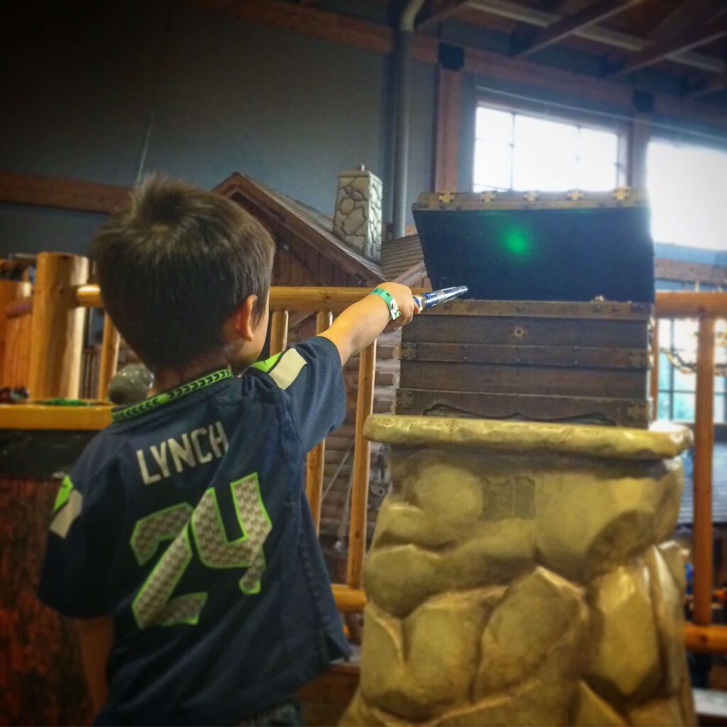 A kid at Great Wolf Lodge playing with a borrowed wand, as a way to save money at Great Wolf Lodge