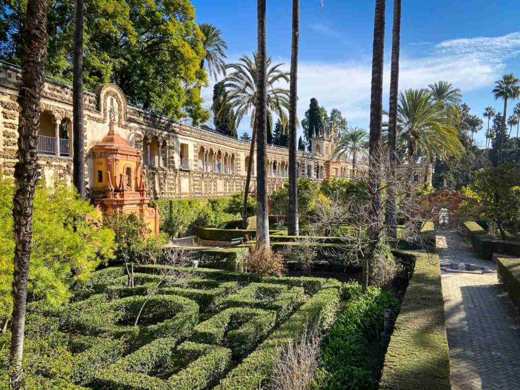 A designed garden with a stone covered walkway in the background and palm trees in the middle