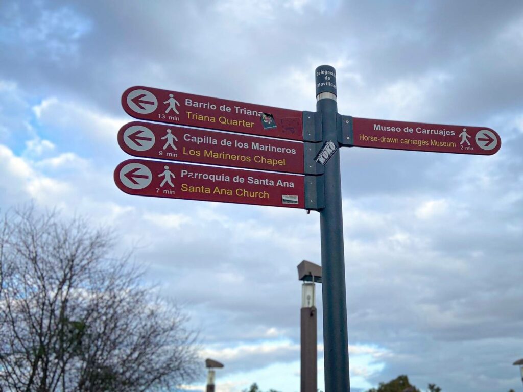 A sign with names and arrows pointing to attractions in Seville