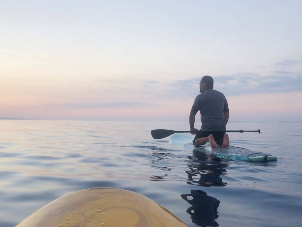 A man paddle boarding while doing fit travel