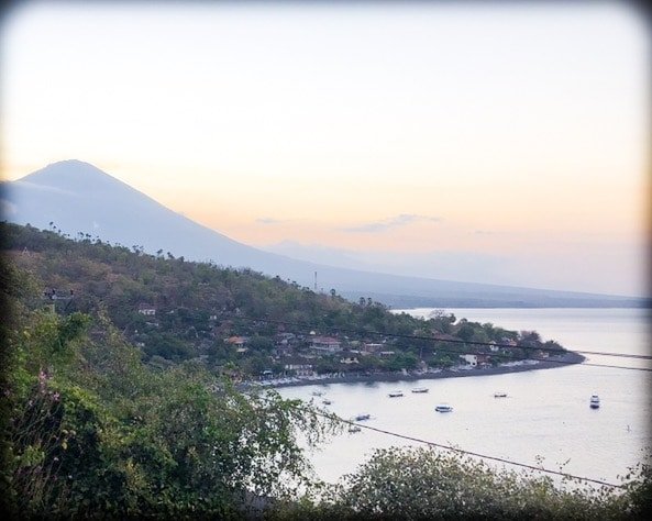 A view of the bay in Amed Bali, as the sun sets behind the mountains in the distance