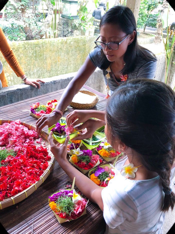 A woman and girl learning to make traditional Balinese offerings and taking part in Bali cultural experiences in Indonesia