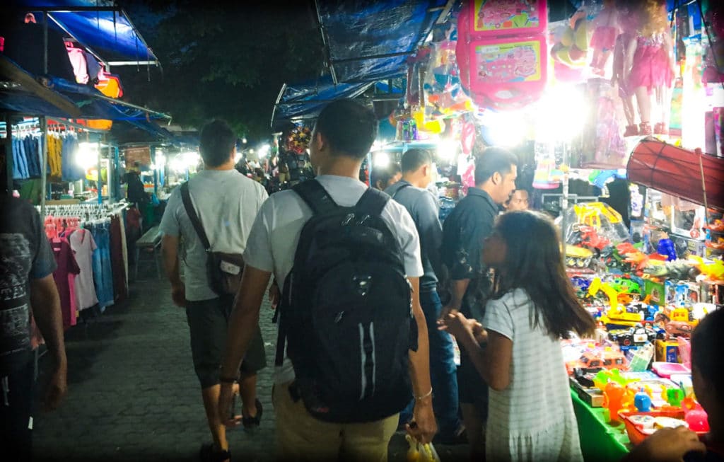 A man and child walking through a night market in Indonesia, traveling like a local