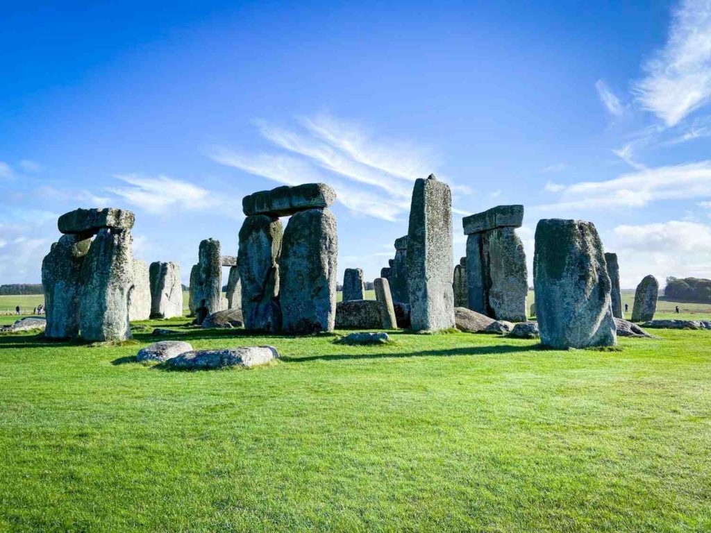Giant stones of Stonehenge on green grass with a blue sky in the background
