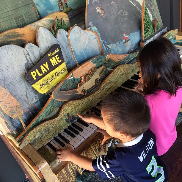 Kids playing on a public piano, one of the fun things about traveling with kids