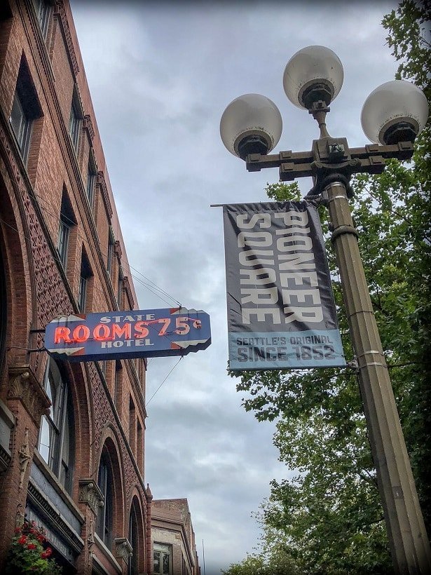 A neon sign and sign of Pioneer Square , examples of things visitors will see during a walking tour of Seattle