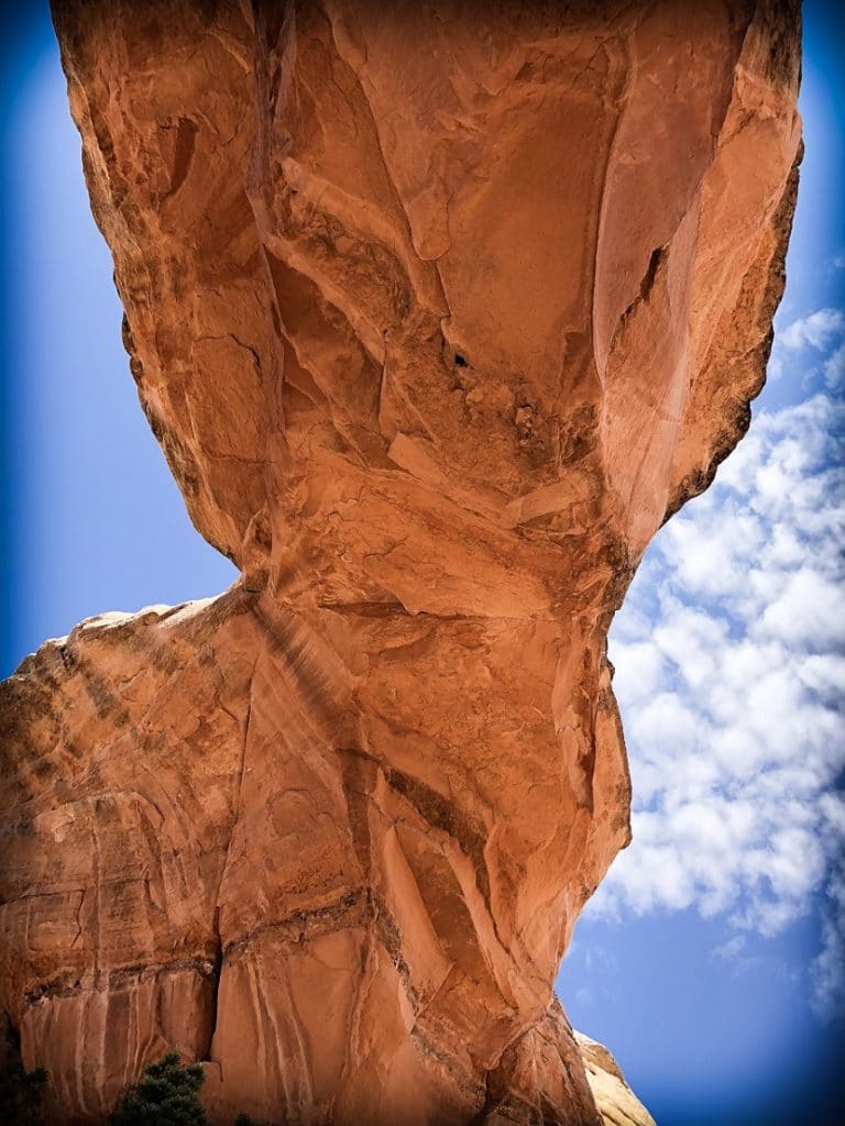 A natural arch against a blue sky with white clouds at Arches National Park, one of the national parks in the west 