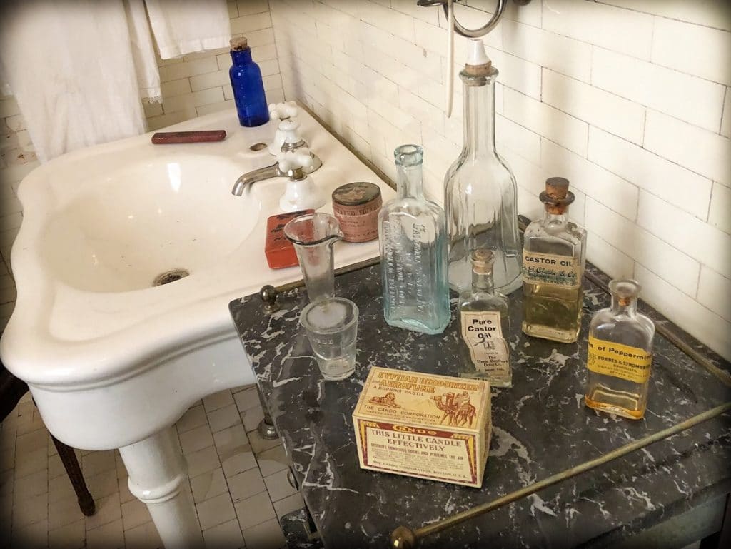 Glass bottles and old fashioned boxes sitting on a marble counter top next to a sink at the Molly Brown House, one of the family friendly Denver experiences that families can do