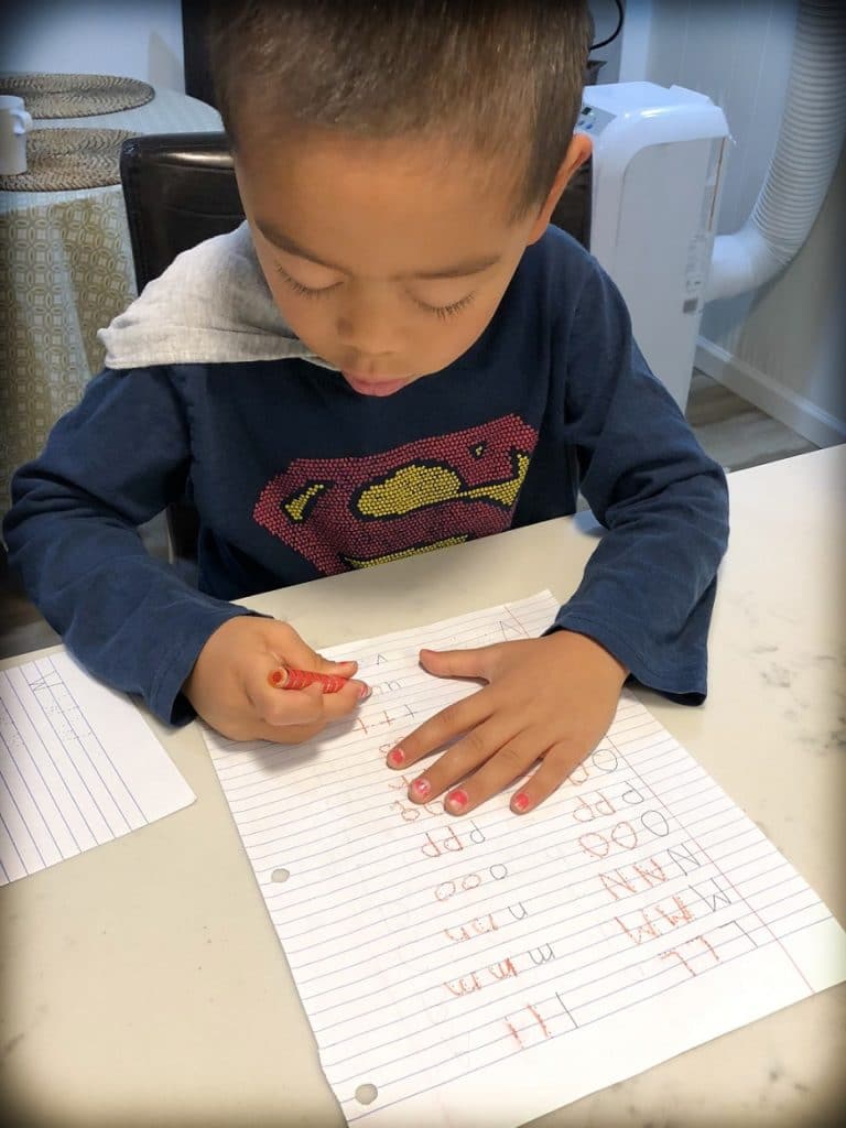 A boy from a worldschooling family practicing how to write letters