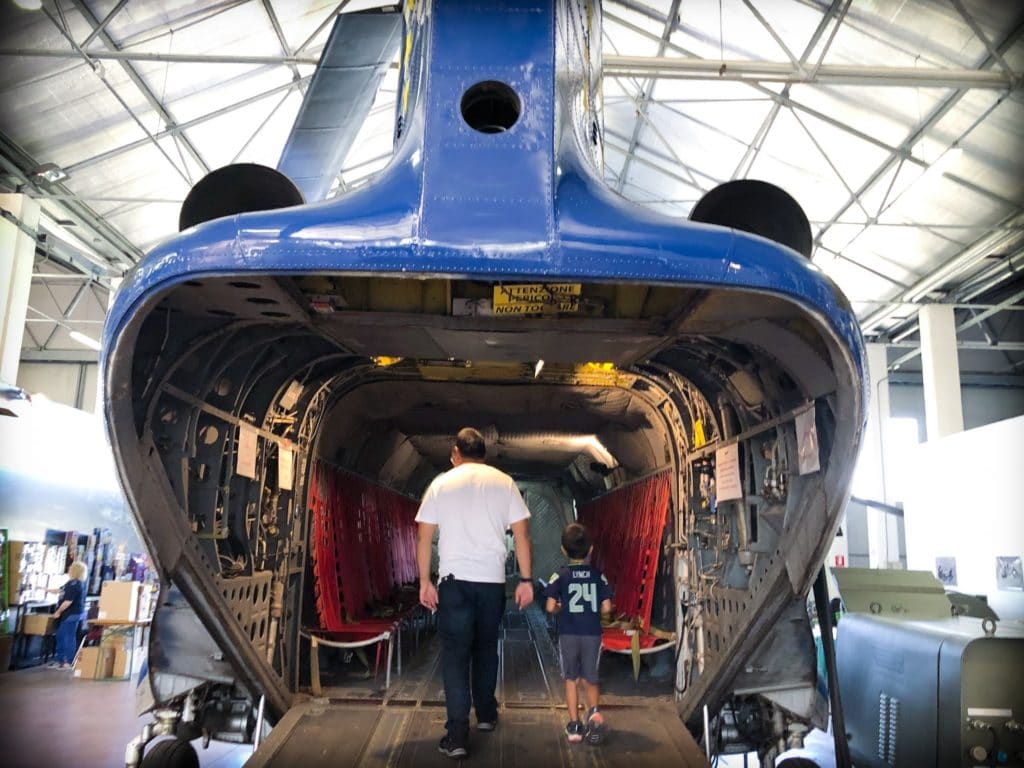 A father and his young son inside of a military cargo plane, which is sitting in a hangar of Volandia museum in Milan, Italy.