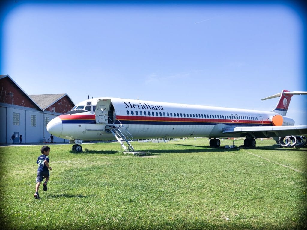 A little boy running towards an old commercial airplane at Volandia museum in Milan, Italy.